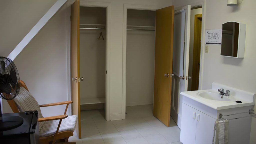 Une pièce avec un lavabo, une chaise et deux grands placards.